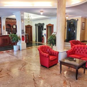 奥里斯塔诺马里亚诺IV皇宫酒店的大堂设有2把红色椅子和桌子