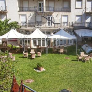 奥里斯塔诺马里亚诺IV皇宫酒店的一个带桌椅和白色遮阳伞的庭院。