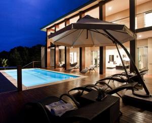彭宁顿Villa Umdoni的一座带游泳池和遮阳伞的房子