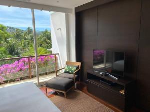苏林海滩Beachfront 2 BR Luxury Condo Chava Surin的一间卧室配有电视、椅子和窗户。