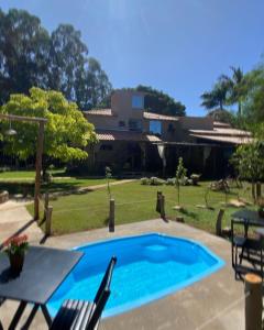 博阿埃斯佩兰萨Pousada do Bosque的一个带桌椅的游泳池和一个房子