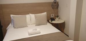 帕斯托HOTEL SANTORI的一张带白色枕头的床和电话