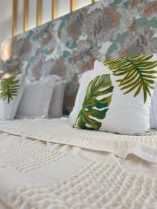 拉加纳斯Eora Studios的一张带白色床单的床和一个带叶子的枕头