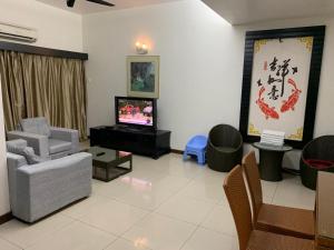 马六甲Homestay at Lagoon Park Resort的客厅配有电视、沙发和椅子