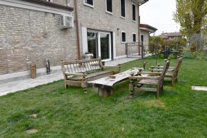 拉文纳La Pineta del Borgo的三个木凳坐在建筑物旁边的草上