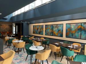 伦敦55酒店的餐厅设有桌椅,墙上挂有绘画作品