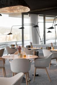 勒布拉索斯Hôtel des Horlogers的餐厅设有桌椅和大窗户。