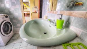 贡内萨Casa Nina的浴室里的一个绿色水槽,上面有饮料