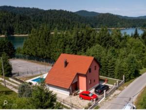 洛克维Gorska Vila Lokvarsko jezero的一座橙色屋顶的房子,前面有一辆汽车