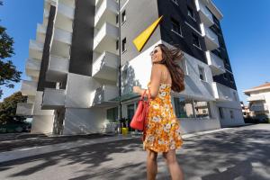 里米尼Nero D'Avorio Aparthotel & SPA的站在建筑物前身穿衣服的女人
