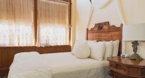 SilvertonTeller House的卧室配有白色的床和木制床头板