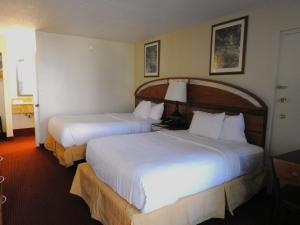 奥兰多Quality Inn Orlando-Near Universal Blvd的酒店客房,配有两张带白色床单的床