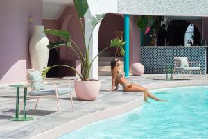 巴伊亚英格莱萨洛卡丝巴西亚酒店的比基尼的女人坐在游泳池旁边