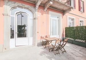 梅纳焦Casa Andrea的粉红色建筑前方带桌椅的庭院