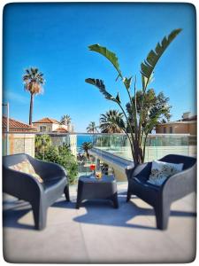 芒通Le Vallaya Suites & Spa的一个带两把椅子和一张桌子的庭院和一棵棕榈树