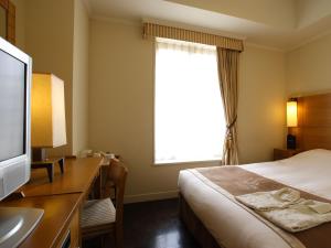 东京银座蒙特利拉苏瑞酒店的酒店客房配有一张床和一张书桌及一台电视