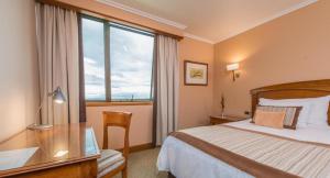 蒙特港太平洋大酒店的配有一张床、一张书桌和一扇窗户的酒店客房