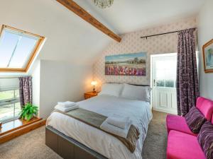 Llanfihangel-yng-NgwynfaHalfen Granary的一间卧室配有一张大床和一张粉红色的沙发