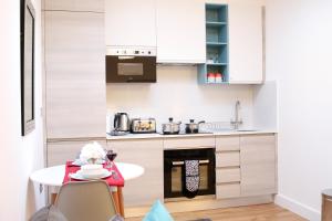 SydenhamHigh Spec Luxury Studio Apartment in Sydenham的小厨房配有白色橱柜和桌子