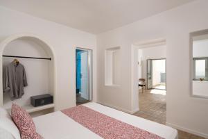 费拉Asha Luxury Suites的一间白色卧室,配有一张床和一个走廊