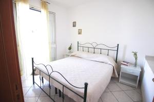 新福卡Villetta Luca by RENTHOUSESALENTO的一间卧室配有一张带白色床单的床和一扇窗户。