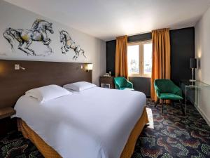 索米尔索米尔卢瓦尔河畔美居酒店的酒店客房设有一张白色大床和一张书桌