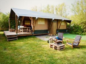 韦斯特卡佩勒Glamped - Luxe camping的庭院前带两把椅子的帐篷
