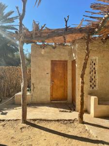 锡瓦Sleep In Siwa的一座带木门和棕榈树的房子