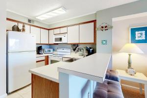 大洋城Hidden Harbour 312C的厨房配有白色橱柜和白色冰箱。
