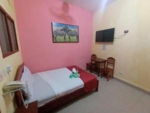 伊基托斯Hospedaje California Inn的卧室设有粉红色的墙壁、一张床和一把椅子
