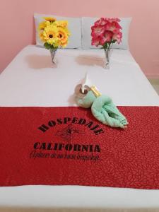 伊基托斯Hospedaje California Inn的一张床上有红毯和鲜花