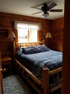 WarrensWarrens Cabin的一间卧室配有一张带吊扇和窗户的床。
