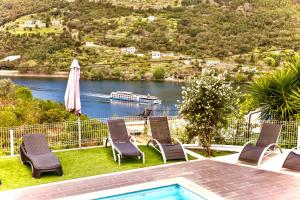 雷森迪Quintinha de Mirão - Douro Valley的一个带椅子和遮阳伞的游泳池以及水上船只