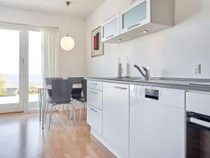 阿灵厄Holiday home Allinge XXII的厨房配有白色橱柜和桌椅