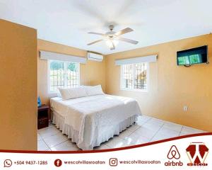 罗阿坦Wescot Villas Comfort的一间卧室配有一张床和吊扇