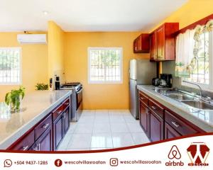 罗阿坦Wescot Villas Comfort的厨房配有橙色墙壁和不锈钢用具