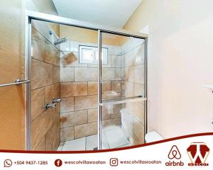 罗阿坦Wescot Villas Comfort的浴室里设有玻璃门淋浴