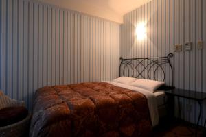 东京樱花芙蓉青山酒店的卧室配有一张床,墙上有灯