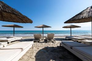 波塞蒂NewStory Luxury Suites Possidi的海滩上设有椅子和遮阳伞,还有大海