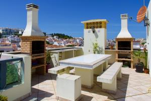 费拉古多Edifício Tomás的阳台设有桌子和长凳,位于屋顶