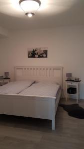 穆赫Ferienwohnung Fichtenweg的一间白色卧室,配有一张床和两张桌子
