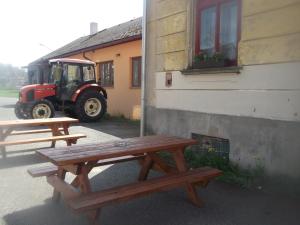 KřižanyRestaurace s ubytováním的两个野餐桌,旁边是一座带拖拉机的建筑
