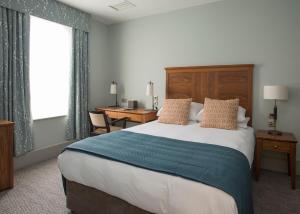 法纳姆Bush Hotel Farnham的酒店客房设有一张大床和一张书桌。