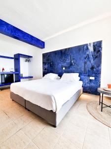 伊利索斯Penélope Hotel的卧室内的一张大床,卧室内有蓝色的墙壁