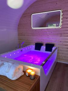威廉堡Apex Studio Pod & Jacuzzi Bath的浴室设有紫色浴缸、蜡烛和灯