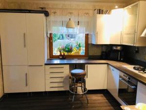 新策勒Waldidyll的厨房配有白色橱柜和凳子