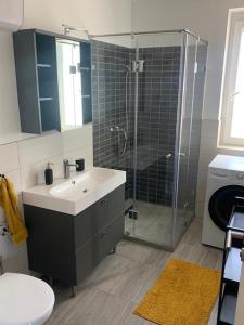 格德勒New Home Guest House的一间带水槽和玻璃淋浴的浴室