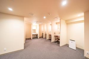 大阪Shinsaibashi ARTY Inn的一间空房间,里面摆放着一排椅子和书桌