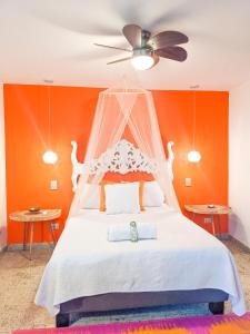 卡利魔法花园之家旅馆的一间卧室配有一张白色的床和橙色的墙壁