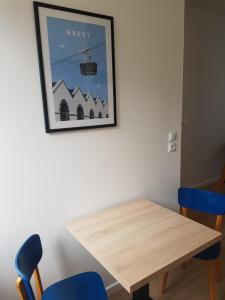 布雷斯特Brest : Beau T1 en centre ville的一张带两张蓝色椅子和照片的餐桌